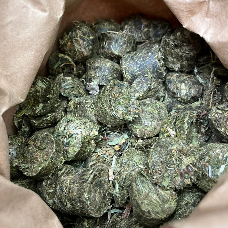 Blick in den geöffneten Papiersack COBS SELEKTION: dunkelgrüne Wiesengras-Cobs mit sichtbaren Blattfasern.